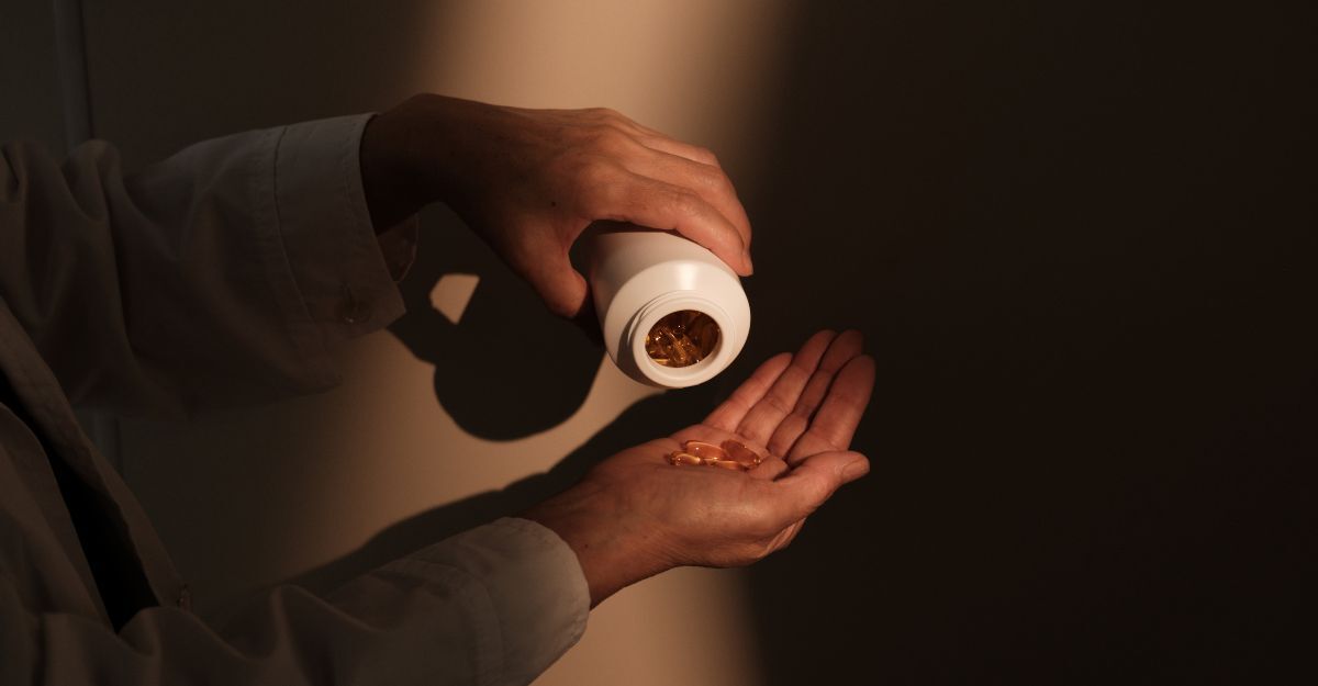 Mani che versano capsule da un flacone.