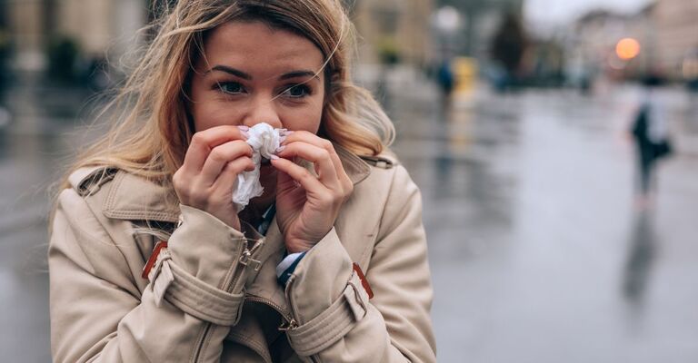 Cosa fare quando si avvertono i sintomi di un’influenza in arrivo donna si soffia il naso infreddolita