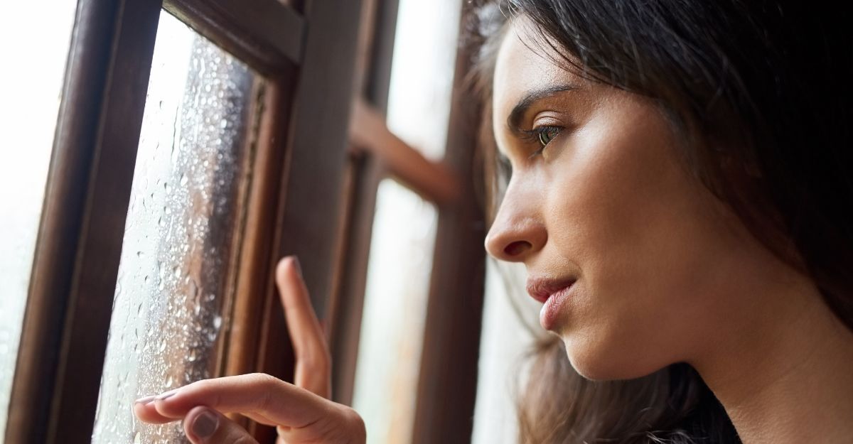 Donna guarda fuori dalla finestra con la pioggia.