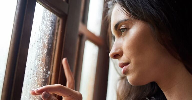 Donna guarda fuori dalla finestra con la pioggia.
