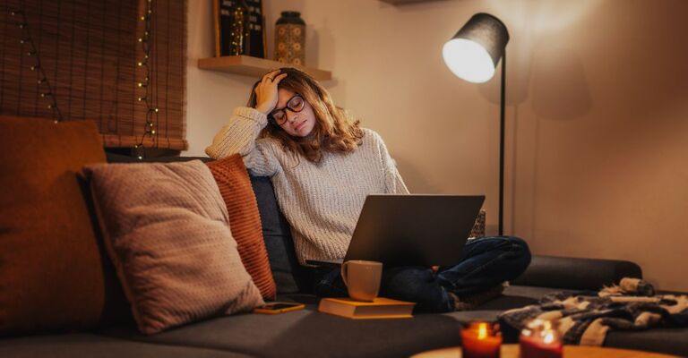 Una giovane donna stanca e frustrata davanti al computer portatile durante il periodo autunno-inverno