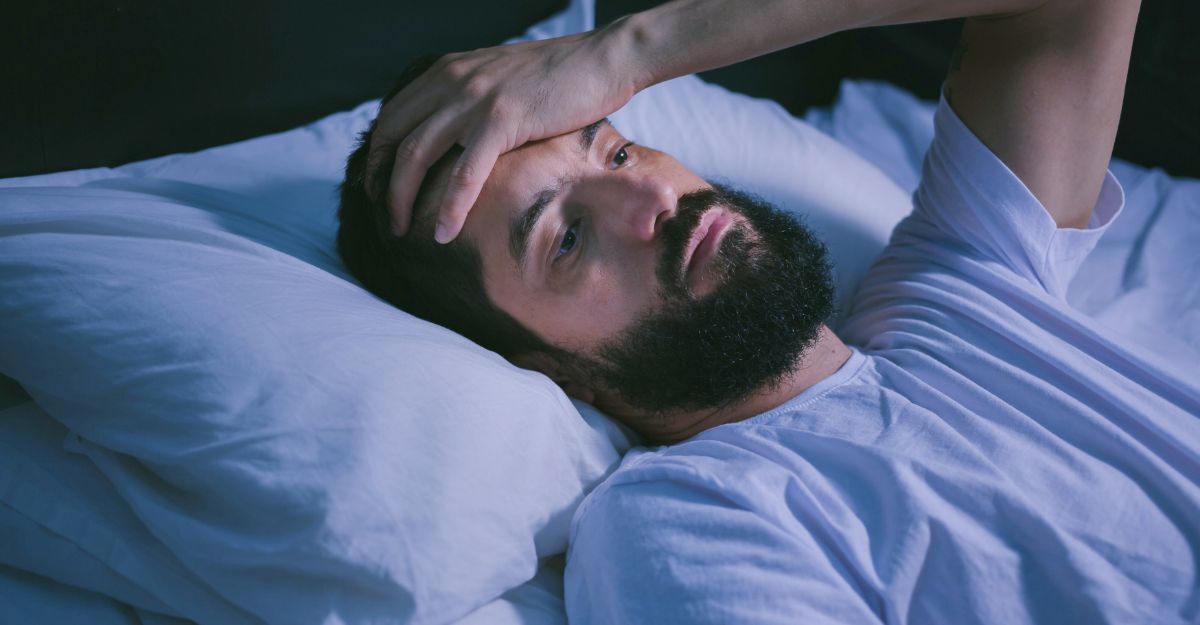 Giovane uomo a letto con gli occhi aperti che soffre di insonnia e disturbi del sonno