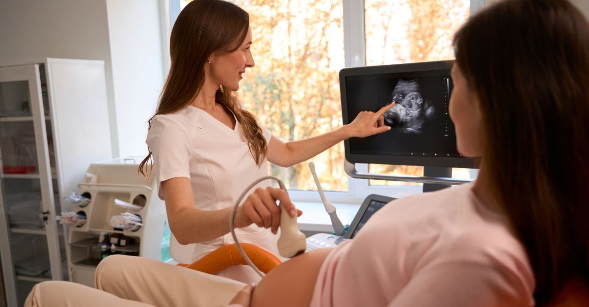 Donna incinta sottoposta a ecografia che osserva il monitor mentre la ginecologa indica
