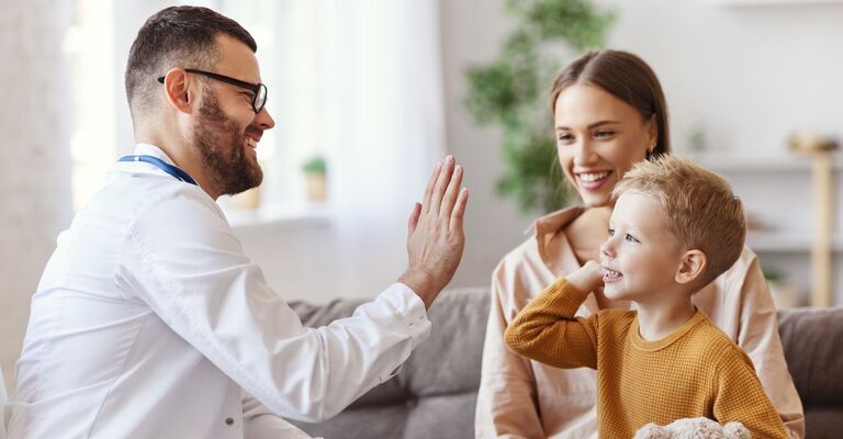 Il medico di famiglia, il pediatra, visita il bambino e gli dà il cinque