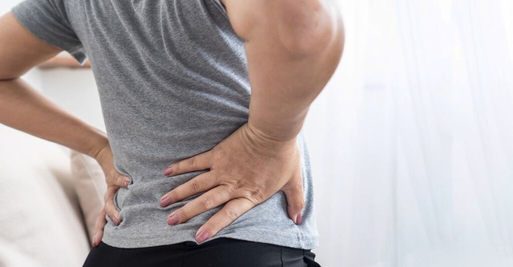 Una donna si tiene la schiena dolente