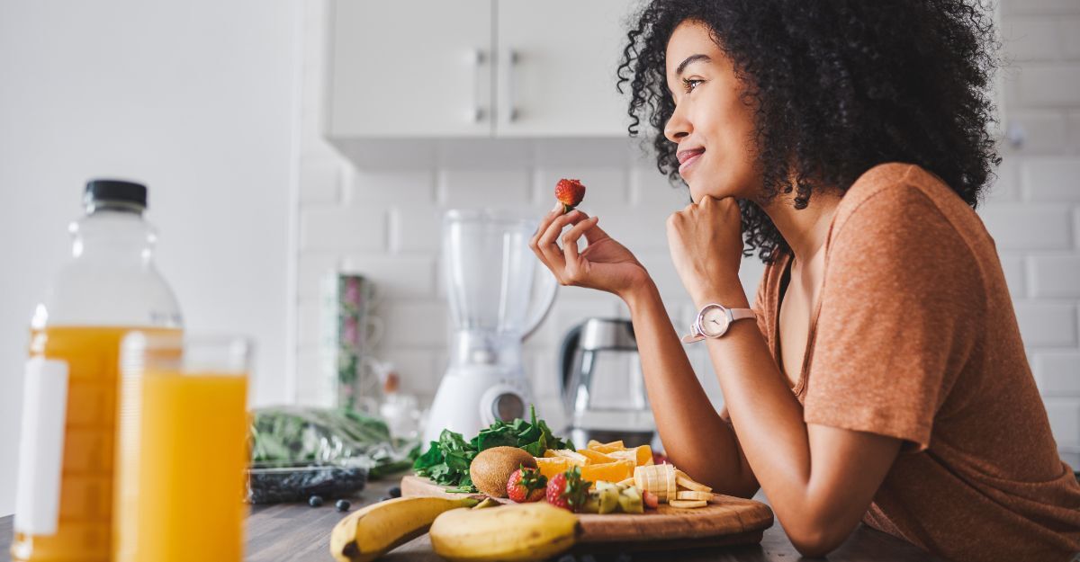 Donna sorridente in cucina con frutta.