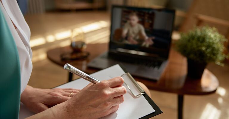 Persona che prende appunti durante una videochiamata di teleterapia.