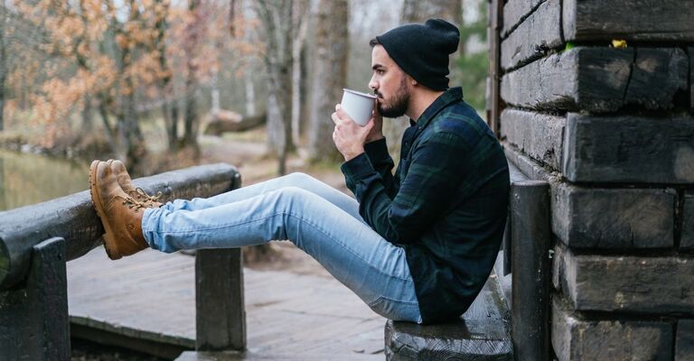 ragazzo malinconico seduto su una panchina, beve un the caldo