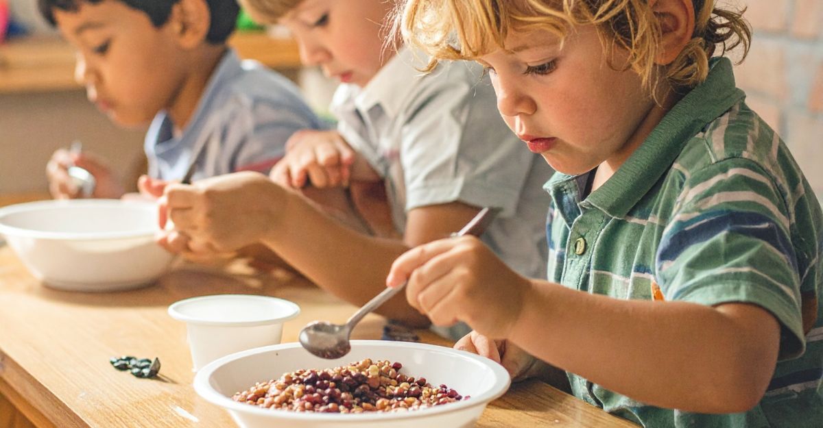 tre bambini seduti al tavolo fanno colazione