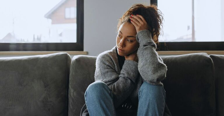 Donna nera triste che soffre di sintomi di depressione e si sente angosciata da sola a casa