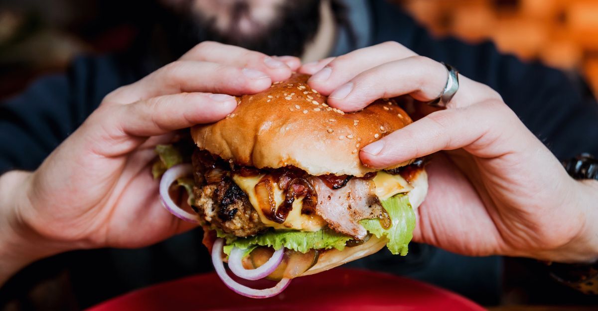Primo piano di un giovane uomo che mangia un cheeseburger