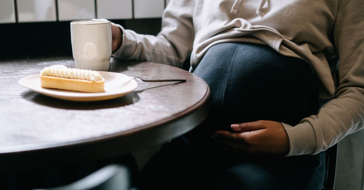 Una donna incinta seduta ad un tavolo con un caffè