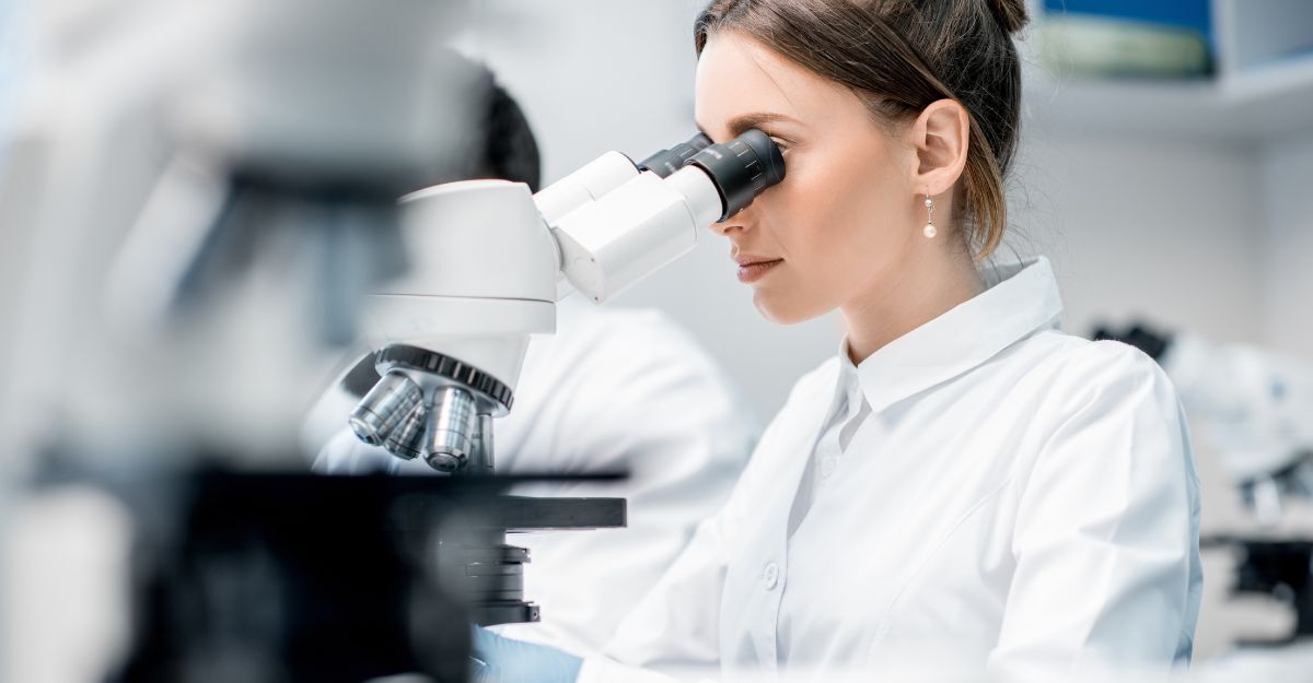 Giovane medico in uniforme che lavora al microscopio eseguendo analisi presso l'ufficio del laboratorio