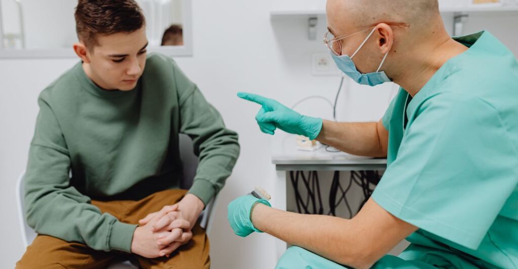 Medico con mascherina che parla con un paziente adolescente