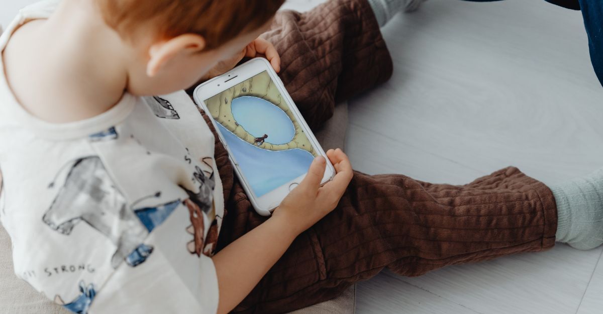 Bambino seduto che guarda lo schermo di uno smartphone.