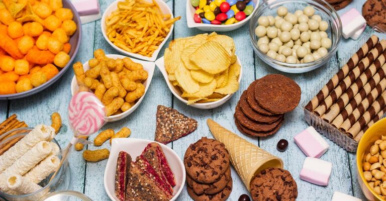 un tavolo colmo di cibo ultra-processato.