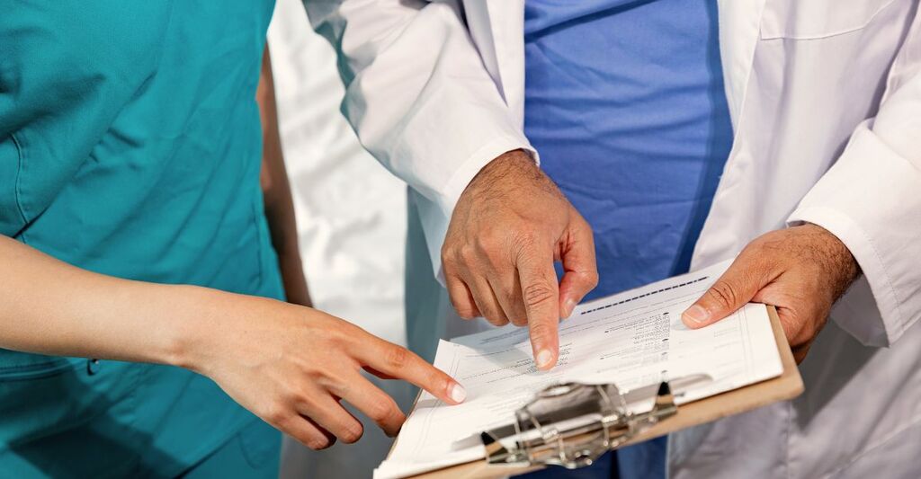 Mani di due medici che indicano un foglio