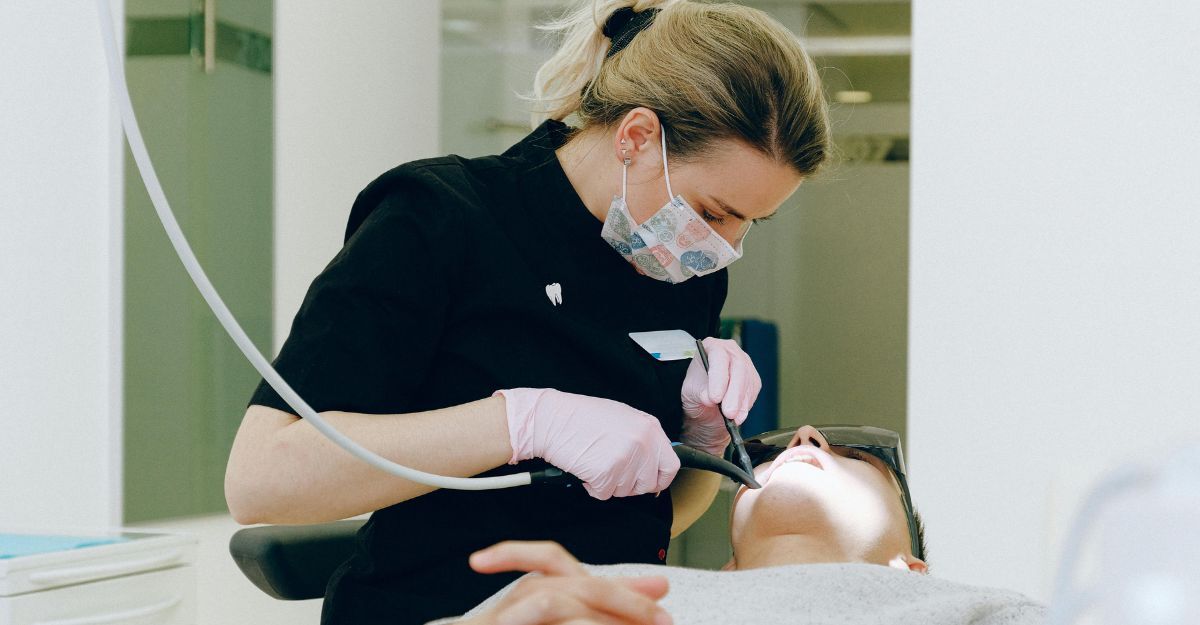 Dentista che, con guanti e mascherina, tiene aperta la bocca del paziente per operare