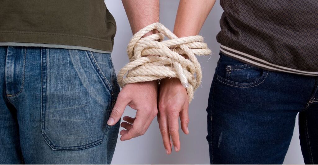 Un uomo e una donna legati insieme da una corda per simboleggiare la dipendenza affettiva nei rapporti di violenza sulle donne.