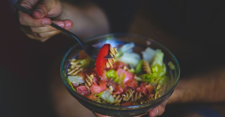 Una persona che mangia un piatto di insalata di notte
