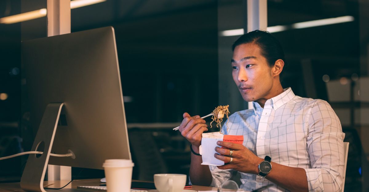 Un ragazzo che mangia di notte davanti al computer
