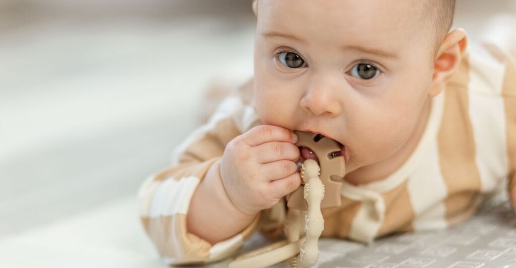 Un bebè che si mette in bocca un giocattolo