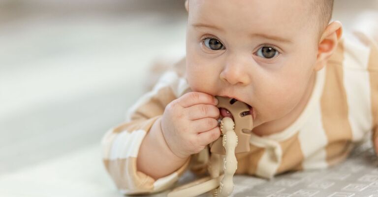 Un bebè che si mette in bocca un giocattolo