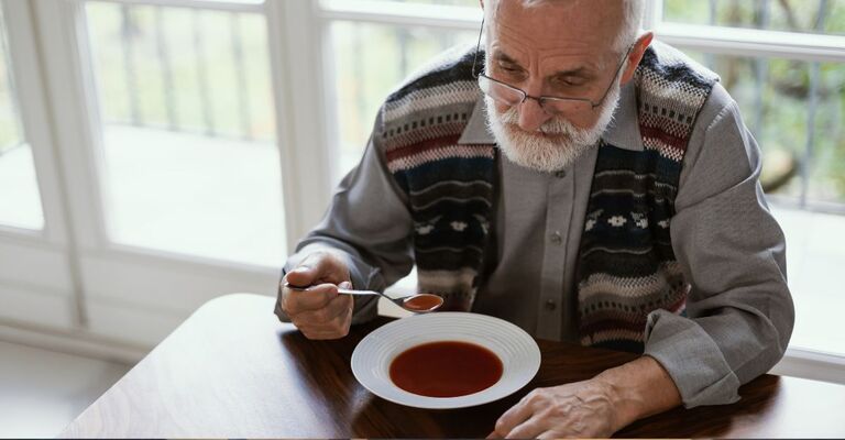 Un uomo sopra i 65 anni mangia da solo.