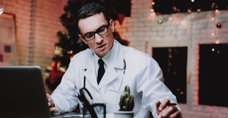 Medico in camice bianco lavora al computer