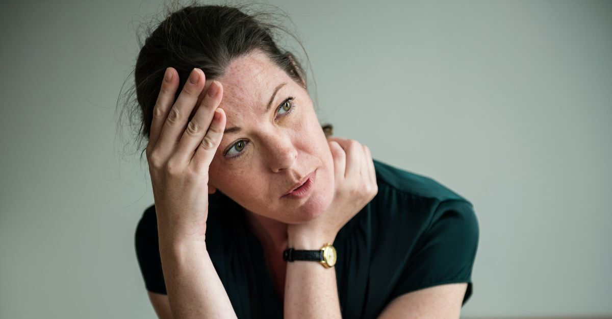Una donna stressata e ansiata con la mano sulla fronte che guarda un punto fisso