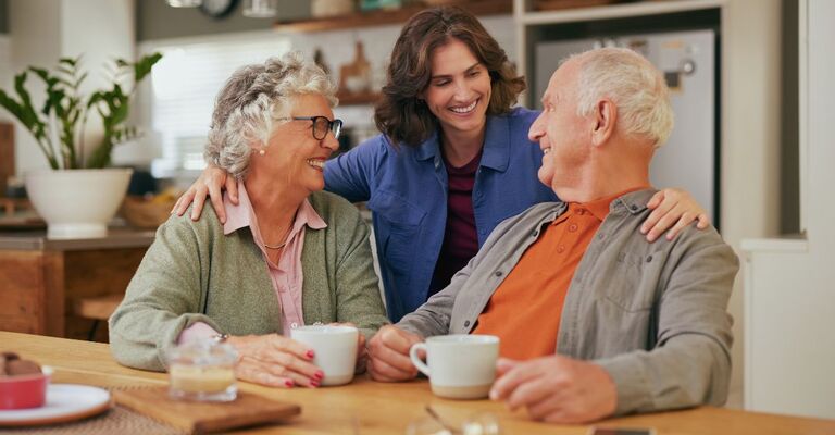 Genitori anziani sorridenti e felici con la figlia adulta che beve il tè