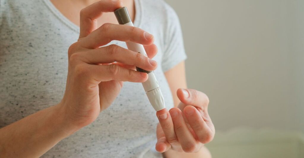 Primo piano di una donna incinta che misura la glicemia con un dispositivo elettronico. Prevenzione essenziale del diabete gestazionale e controllo della salute in gravidanza.