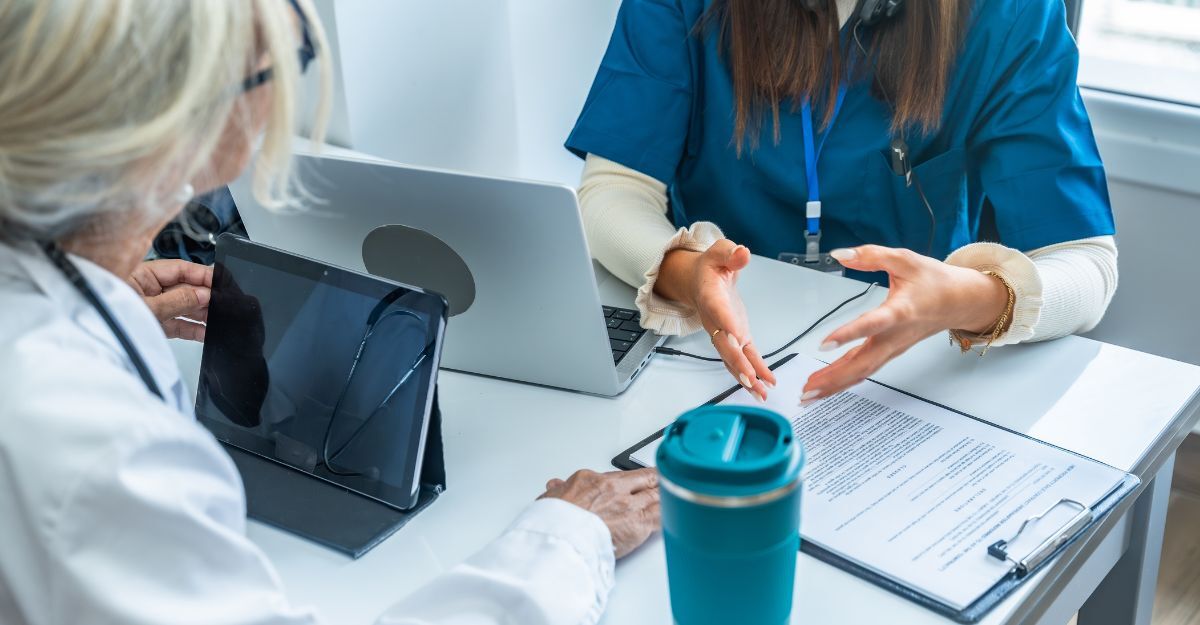 Due medici seduti a un tavolo con un laptop e documenti.