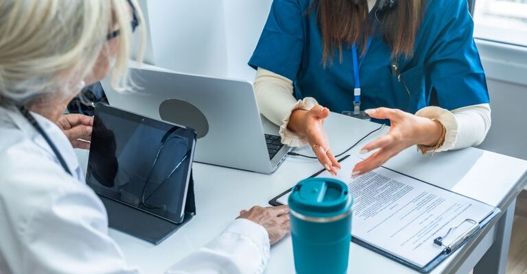 Due medici seduti a un tavolo con un laptop e documenti.