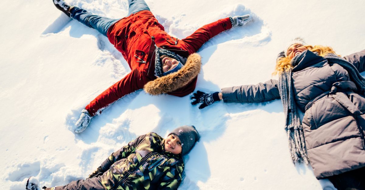 Una famiglia sdraiata sulla neve fa gli angeli di neve