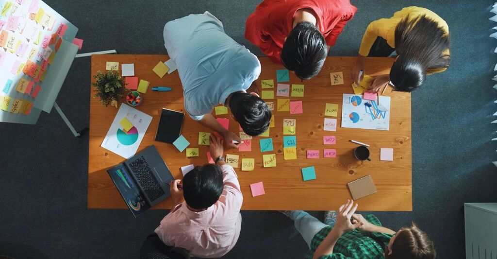 Vista dall'alto di un project manager al lavoro mentre il team di marketing supporta le sue prestazioni. Un'imprenditrice caucasica che lavora insieme a un gruppo di persone intelligenti sceglie un'idea durante una riunione.