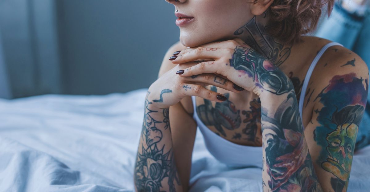 Primo piano di una ragazza tatuata e sognante sdraiata sul letto