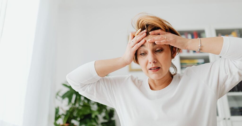Donna stressata si tiene la fronte con una mano