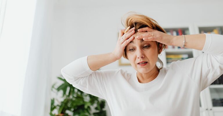 Donna stressata si tiene la fronte con una mano