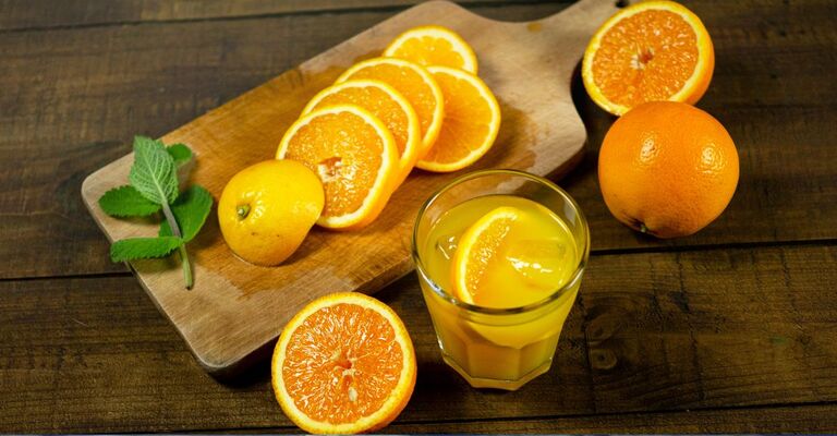 tagliere con arance e bicchiere di spremuta