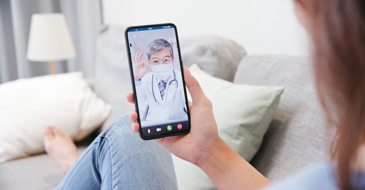 Videoconsulto medico su smartphone con un dottore che indossa una mascherina