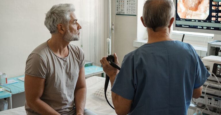 Il medico spiega i risultati della colonscopia al paziente utilizzando le immagini del monitor
