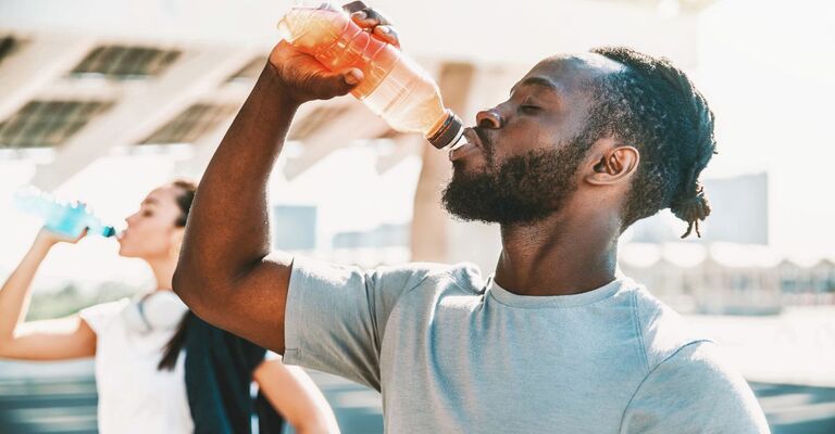 Atleta nero in forma che beve una bevanda energetica all'aperto. Persone in forma che si riposano dopo l'allenamento.