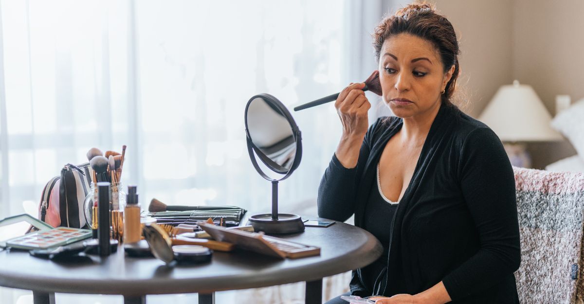 Donna adulta si trucca davanti a uno specchio su un tavolo