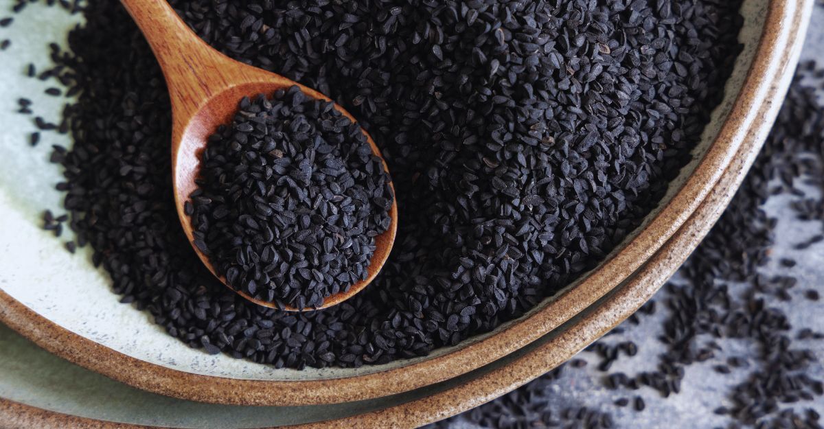 Piatto di spezie indiane. Semi di cumino nero (nigella sativa o kalonji) da vicino con un cucchiaio di legno
