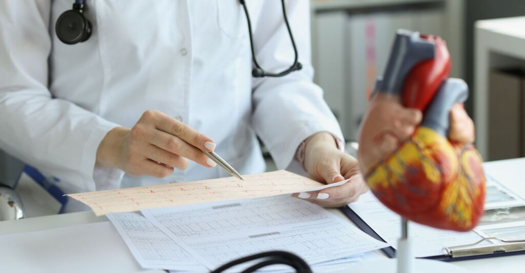 Medico cardiologo che tiene in mano e legge il referto dell'ECG di un paziente con malattia cardiaca