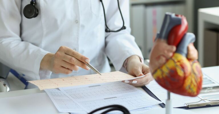 Medico cardiologo che tiene in mano e legge il referto dell'ECG di un paziente con malattia cardiaca