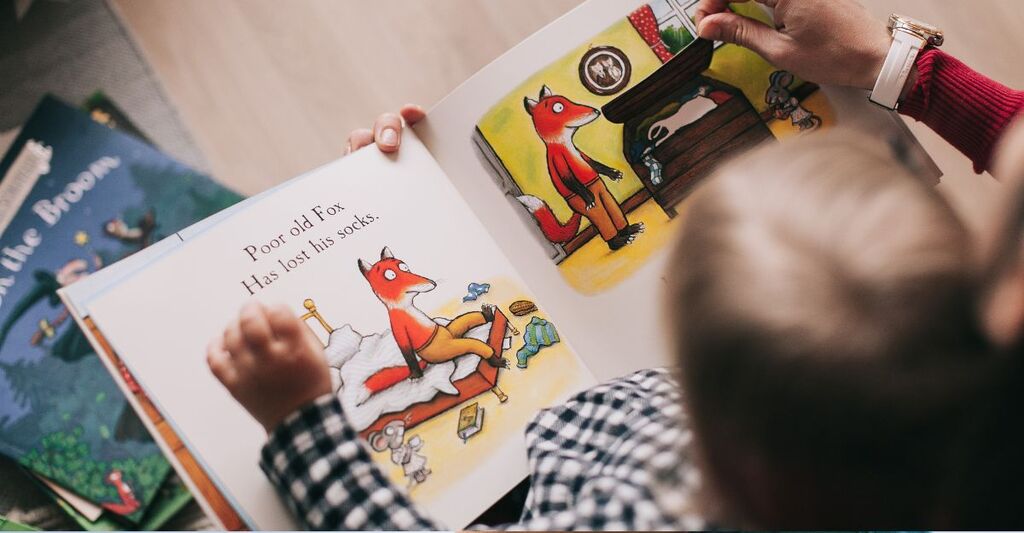 bimbo legge un libro con raffigurata una volpe