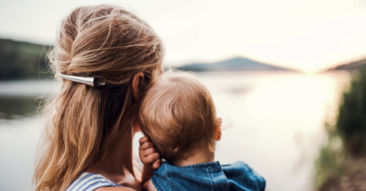 Vista posteriore di una madre con la figlia piccola all'aperto, vicino al fiume, in estate.