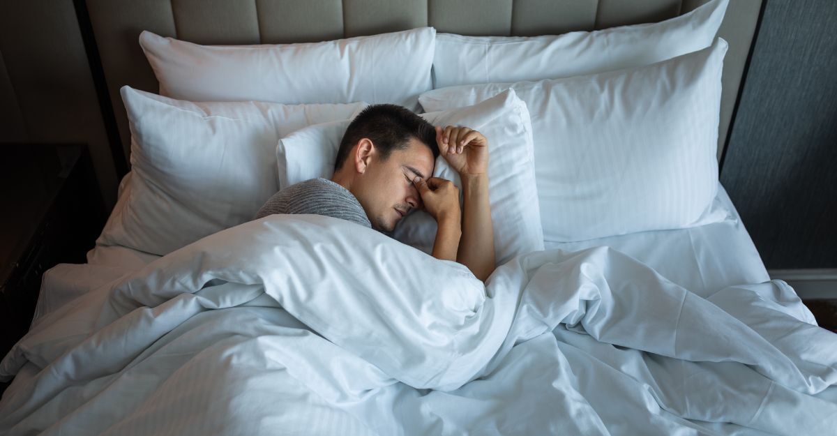 L'uomo esausto non riesce a dormire. Si tiene la testa tra le mani mentre è sdraiato nel letto.